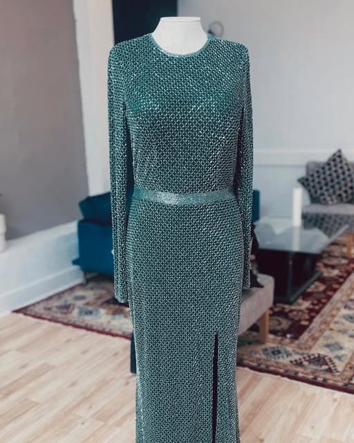 Beaded teal long-sleeve gown fitted on a dress form